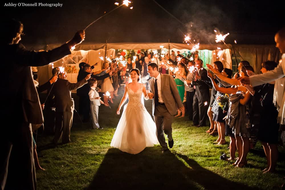 Bride and groom walking through sparklers at wedding reception.