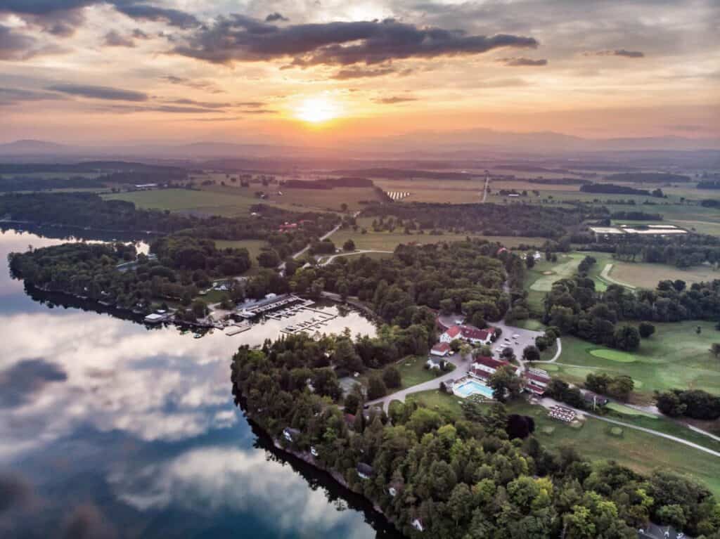 Scenic aerial view of Basin Harbor at sunset with lake and lush greenery.
