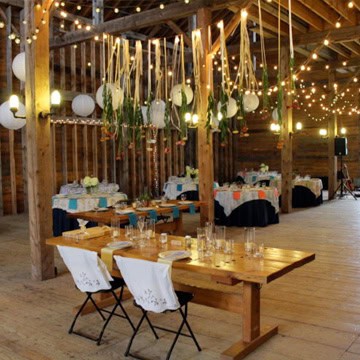 Elegant wedding reception setup with string lights and hanging decorations.