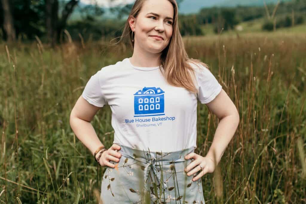 Woman wearing Blue House Bake Shop T-shirt outdoors in a field.
