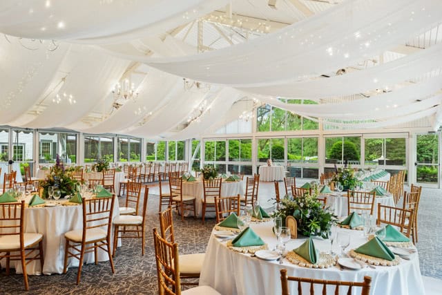 Elegant wedding reception setup at Essex Resort & Spa with draped ceiling and round tables.