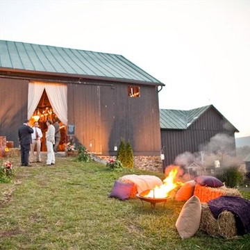 Outdoor wedding scene with fire pit and rustic barn in Vermont.