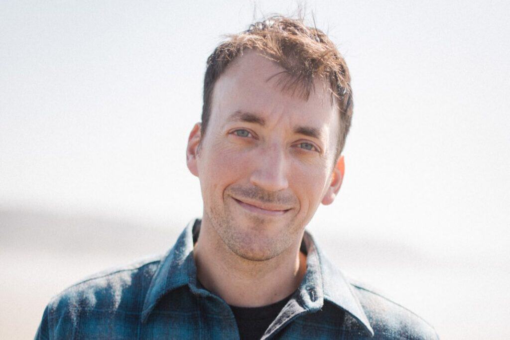 Portrait of a smiling man in casual attire outdoors in Vermont.