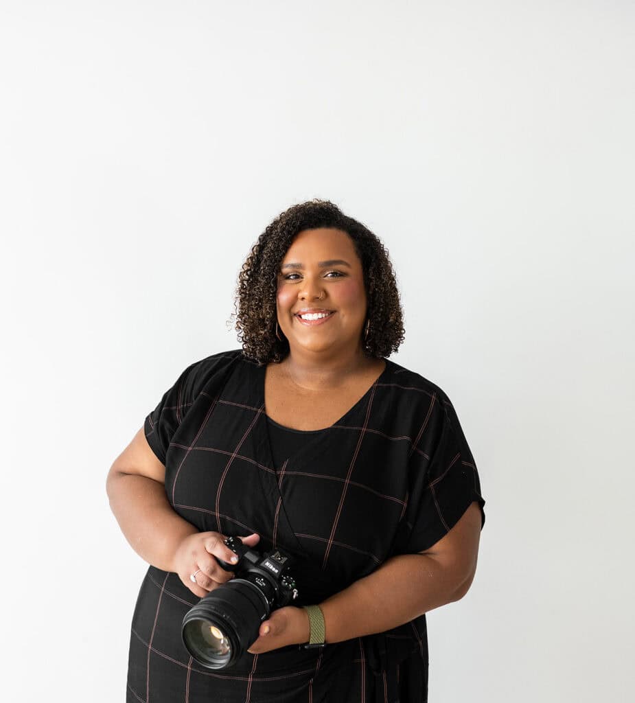 Portrait of a smiling woman holding a camera for wedding photography.