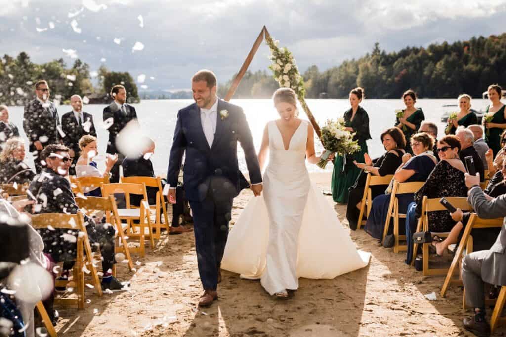 Bride and groom walking down the aisle at outdoor Vermont wedding by the lake.