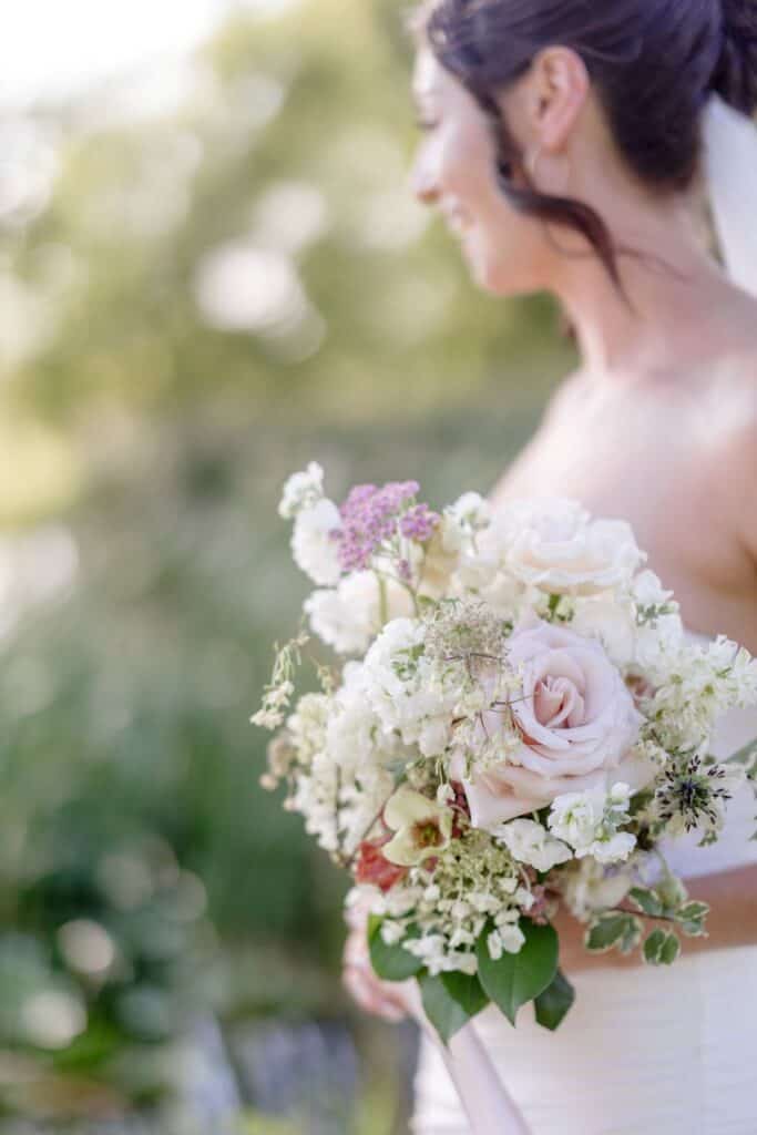 Bride holding a beautiful wedding bouquet in Vermont outdoor setting.