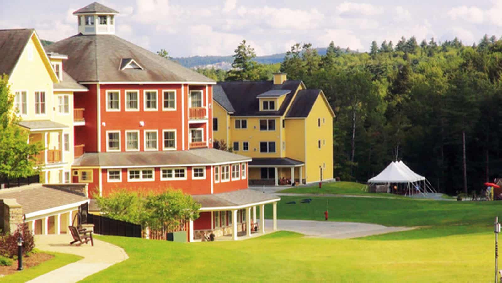 Colorful Vermont resort buildings with lush green landscape and a white event tent.