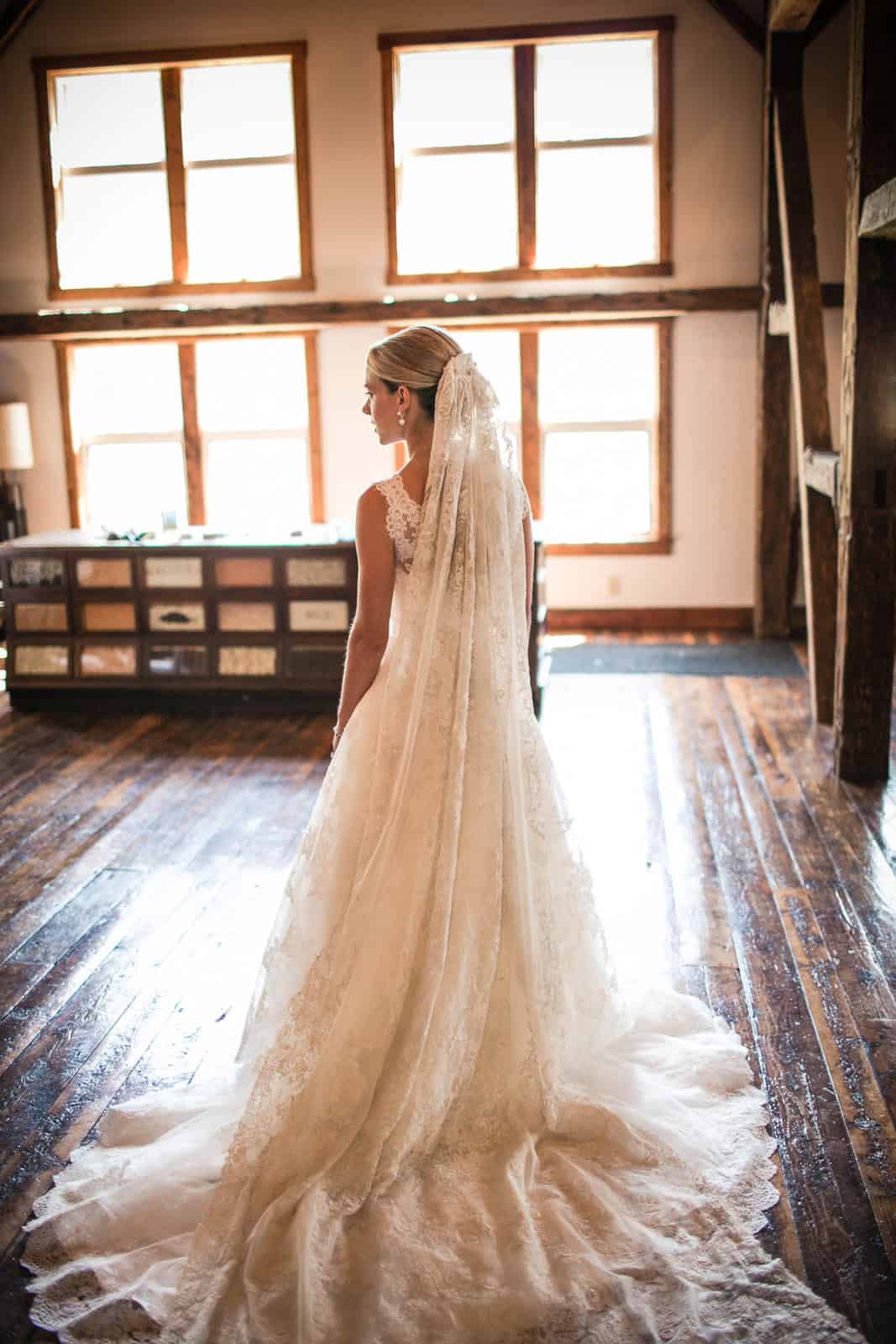 Bride in wedding dress with veil in rustic indoor setting.