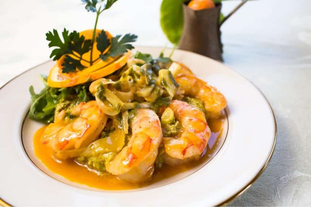 Gourmet shrimp with vegetables on a white plate for wedding catering.