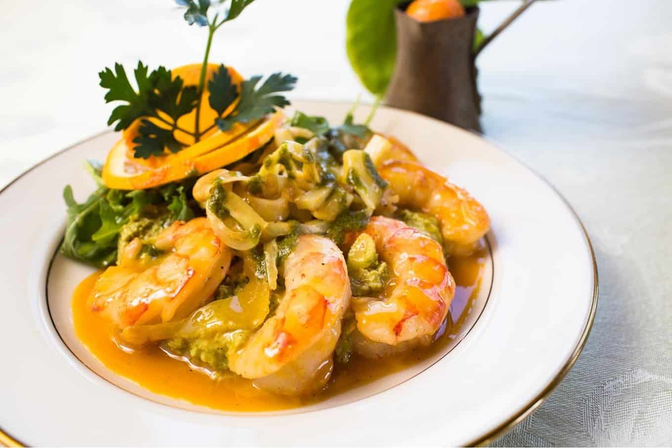 Gourmet shrimp with vegetables on a white plate for wedding catering.