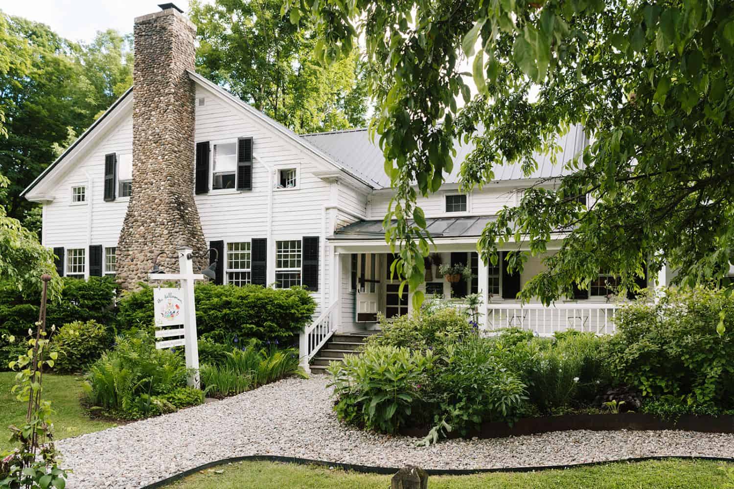 Charming white wedding venue surrounded by lush greenery in Vermont.