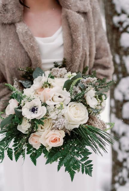 Elegant wedding bouquet with roses and greenery in Vermont winter setting.